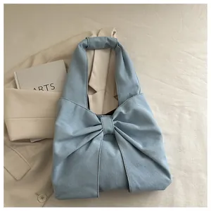 Détail d'un sac à épaule en jean bleu clair avec un design de nœud élégant