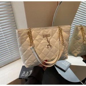 Detail of white quilted tote bag with gold chain strap and deer charm pendant