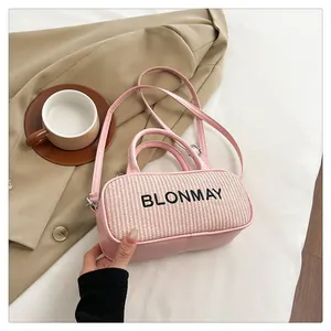 Pink patchwork bag with straw texture and leather handles displayed on a stylish suit