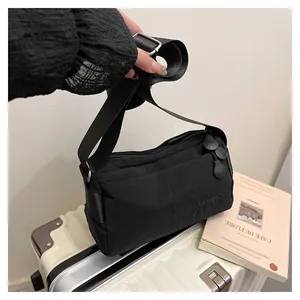 Détail du sac bandoulière noir en nylon avec logo DUONING et tirette de fermeture ronde