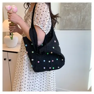 Detail of hand-crocheted black tote bag featuring vibrant colorful pearls and knit texture