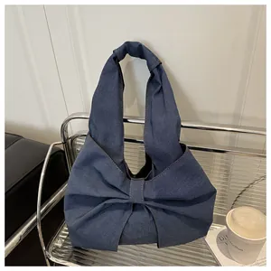 Vue détaillée du sac bandoulière en jean bleu avec un grand nœud décoratif élégant