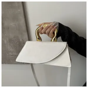 Détail d'un sac blanc avec poignée dorée et bandoulière en cuir réglable amovible