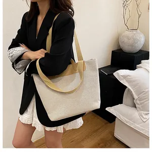 Detail of large canvas tote bag with ginger yellow straps on model in casual suit