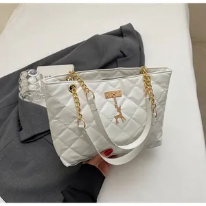 Detail of white quilted tote bag featuring golden chain strap and deer charm pendant