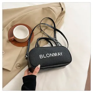 Detail of black woven baguette bag showing the BLONMAY logo and textured leather finish