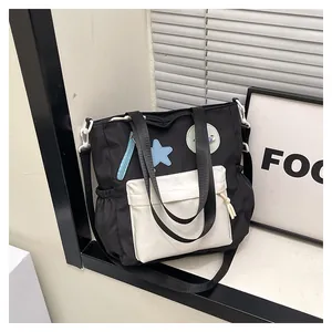 Detail einer schwarzen Canvas-Tasche mit weißer Tasche, Stern-Patch und Kordelzug seitlich