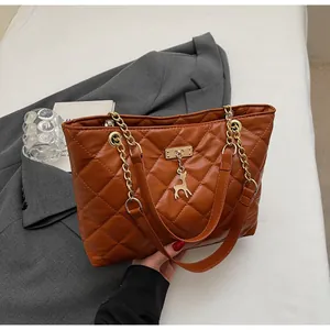 Detailed close-up of brown quilted tote bag featuring golden chain and deer charm detail
