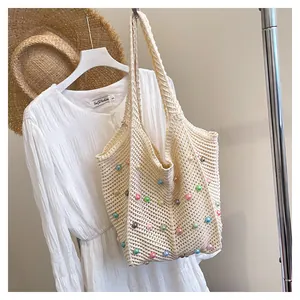 Detail of hand-woven cream tote bag with colorful bead accents and summer resort style