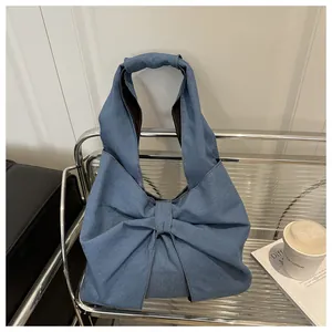 Détail d'un sac à épaule en jean bleu avec grand nœud sur une étagère argentée