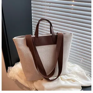 Close-up of oatmeal canvas tote bag featuring brown leather handles and woven texture