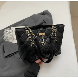 Detail view of black quilted tote bag with gold chain strap and cute deer charm