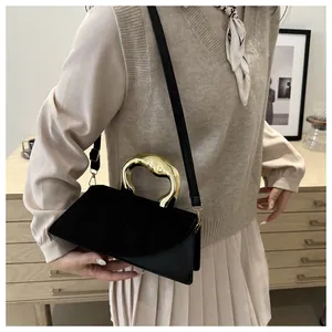 Détail d'un sac noir chic avec poignée dorée sculpturale et textures de cuir mélangées