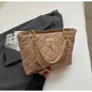 Close-up of quilted pattern tote bag with gold chain strap and deer charm detail