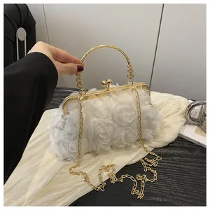 Dettaglio della borsa da sera con fiori 3D bianchi, manico dorato e tracolla a catena