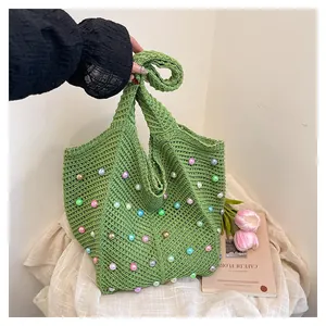 Detail of woven green tote bag featuring colorful pearl beads and soft knot handle