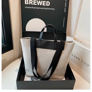 Canvas tote bag with black leather handles shown inside an elegant gift box set