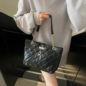 Quilted black leather tote bag with gold chain strap and deer pendant shown in daily use