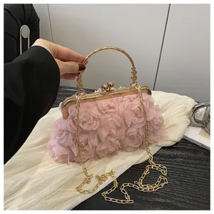 Dettaglio ravvicinato dei petali di rosa in chiffon rosa e manico dorato della borsa