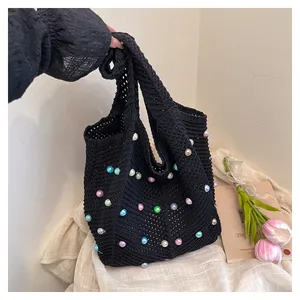 Detail of black woven tote bag featuring colorful faux pearls and crochet texture