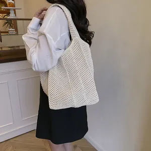 Sac fourre-tout en tricot crème avec large bandoulière présenté dans un décor lifestyle