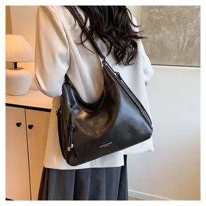 Model wearing a large black hobo shoulder bag with fashion slogan and metallic zipper