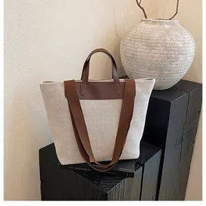 Detail of minimalist canvas tote with premium brown leather handles and stitching