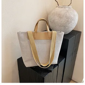 Close-up of beige canvas tote with leather handles on a rustic wooden stand