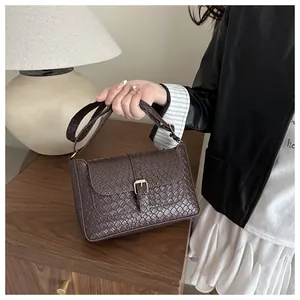 Close-up detail of vintage brown woven texture and gold metal buckle on a shoulder bag