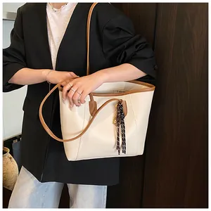 Detail of cream tote bag with litchi grain leather texture and woven rope charm