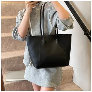 Detail shot of black leather tote bag featuring rich pebble texture and long slim handles