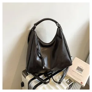 Detail of dark brown leather tote featuring decorative side zipper and knotted tassel pendant