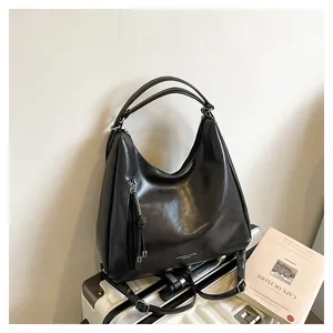Detail of black leather tote bag with tassel charm on a suitcase for travel use