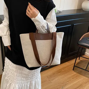 Minimalist canvas tote bag with brown leather handles and adjustable shoulder strap