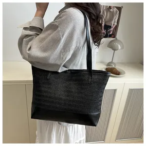Detail of a casual black woven straw tote bag with premium leather splicing design