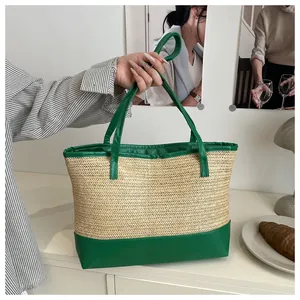 Close-up of contrast straw woven tote bag featuring vibrant green leather handles and base