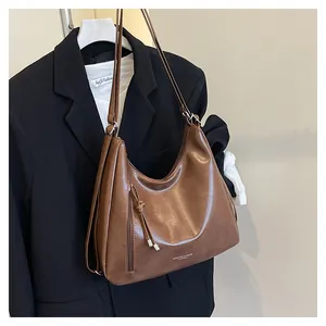 Detail of vintage brown PU leather hobo bag with fringe zipper and embossed logo