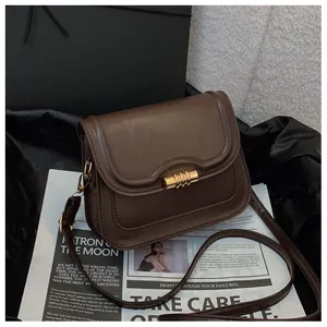 Detail of vintage dark brown faux leather bag with gold metal twist lock and strap