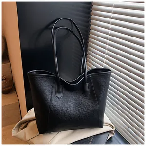 Detail shot of the pebble-grain texture and embossed logo on this black leather tote bag