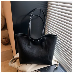 Close-up of black lychee leather tote bag with thick texture and shoulder straps