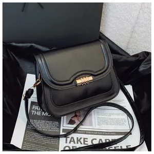 Detail of a vintage black leather crossbody bag with an elegant gold cylindrical clasp