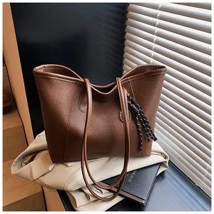 Detail shot of brown leather tote bag with braided charm and light shadows