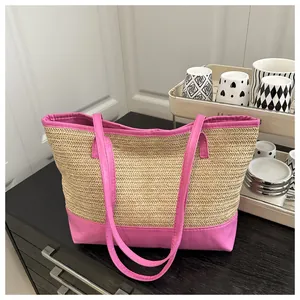 Detail of handwoven straw tote featuring vibrant magenta faux leather straps and trim