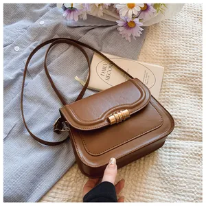 Detailed view of a vintage brown leather shoulder bag with a gold textured metal buckle