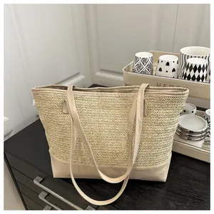 Close-up of woven straw texture and beige leather trim on a large shoulder tote bag