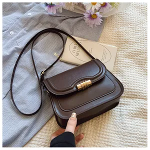 Macro shot of brown faux leather bag featuring wave-edge flap and golden metal buckle