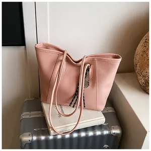 Close-up of pink litchi grain leather tote bag with stylish braided tassel detail
