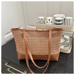 Detail of herringbone straw weave and brown faux leather base on a large tote bag