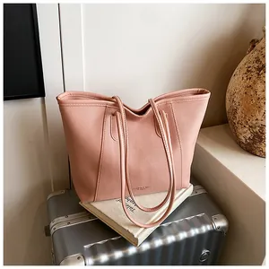 Pink lychee-grain tote bag on a silver suitcase with a vase in a sunny lifestyle setting