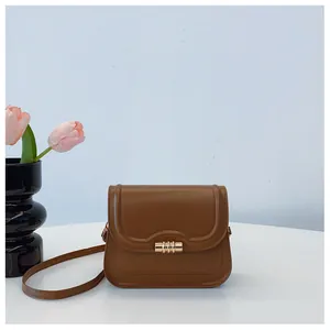 Detail view of the vintage brown leather shoulder bag with gold cylindrical clasp